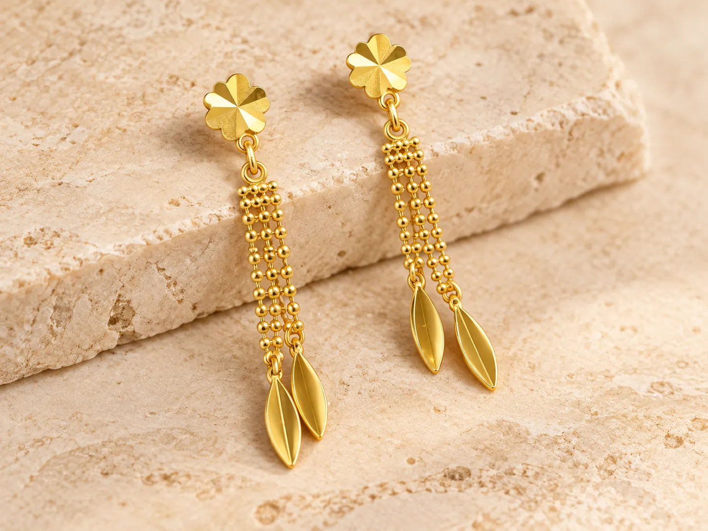 Pair of long gold drop earrings with beaded chains ending in leaf-shaped pieces