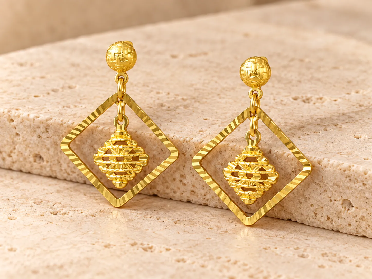 Pair of gold drop earrings with diamond-shaped open frames around a pierced centre piece