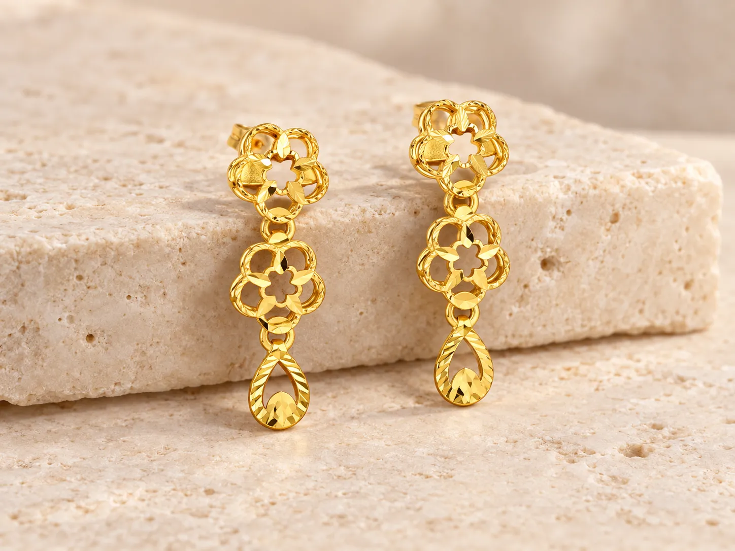 Pair of gold drop earrings with openwork flower shapes and a teardrop end