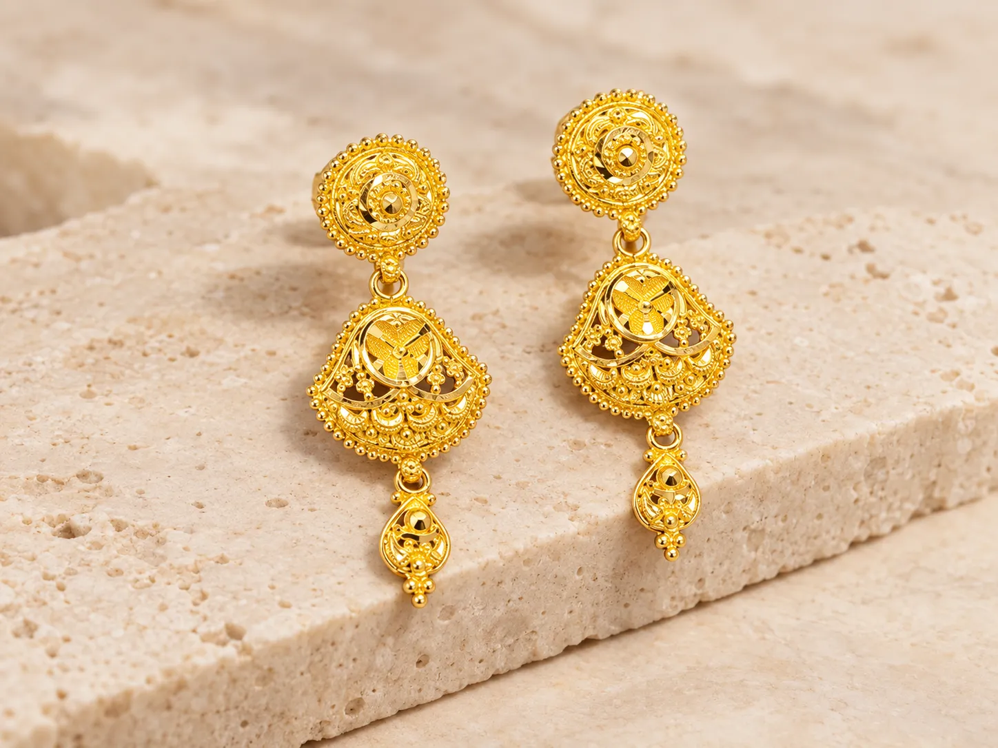 Pair of gold drop earrings with round tops and a decorated pendant section with small beads