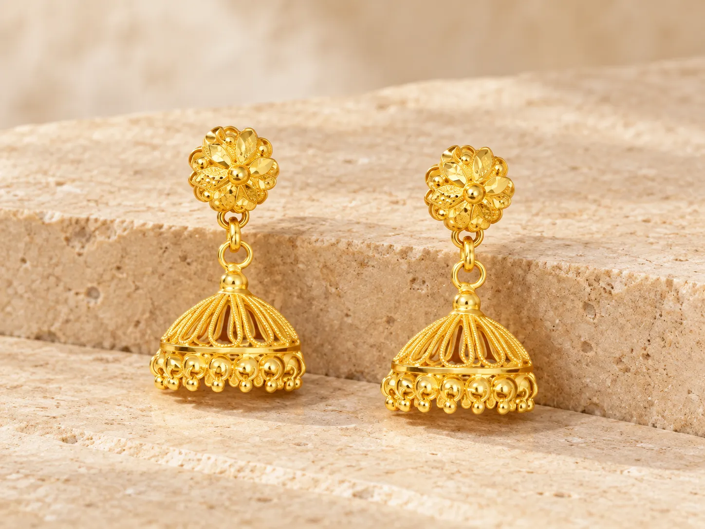 Pair of gold earrings with flower-shaped tops and dome-shaped drops with small hanging beads