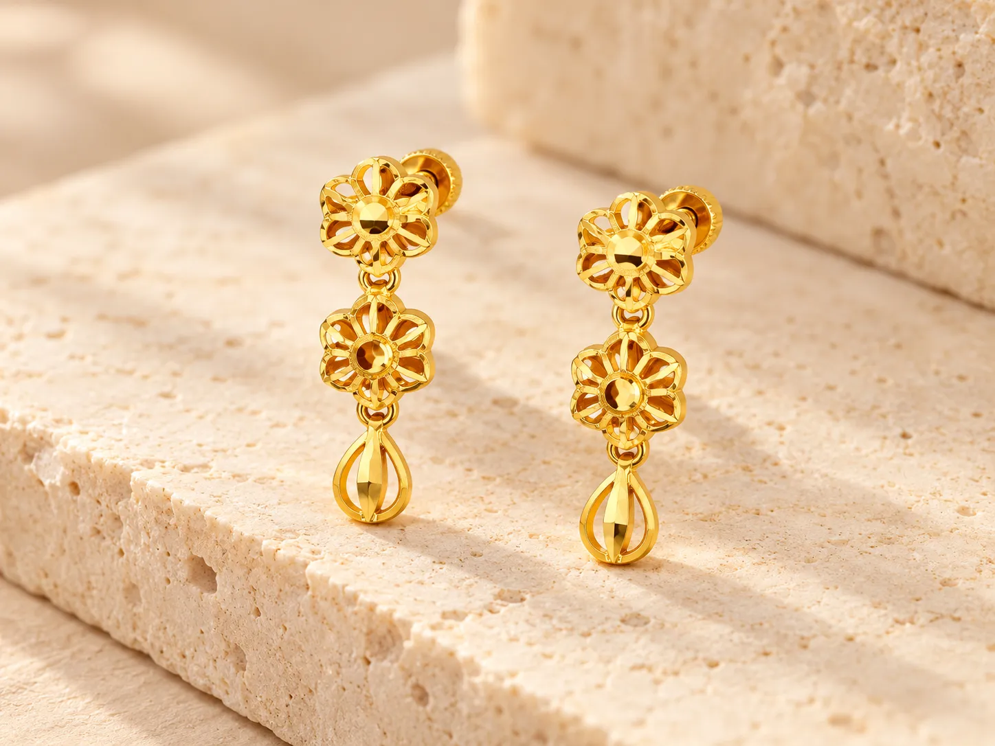 Pair of gold drop earrings with flower shapes and an open teardrop end