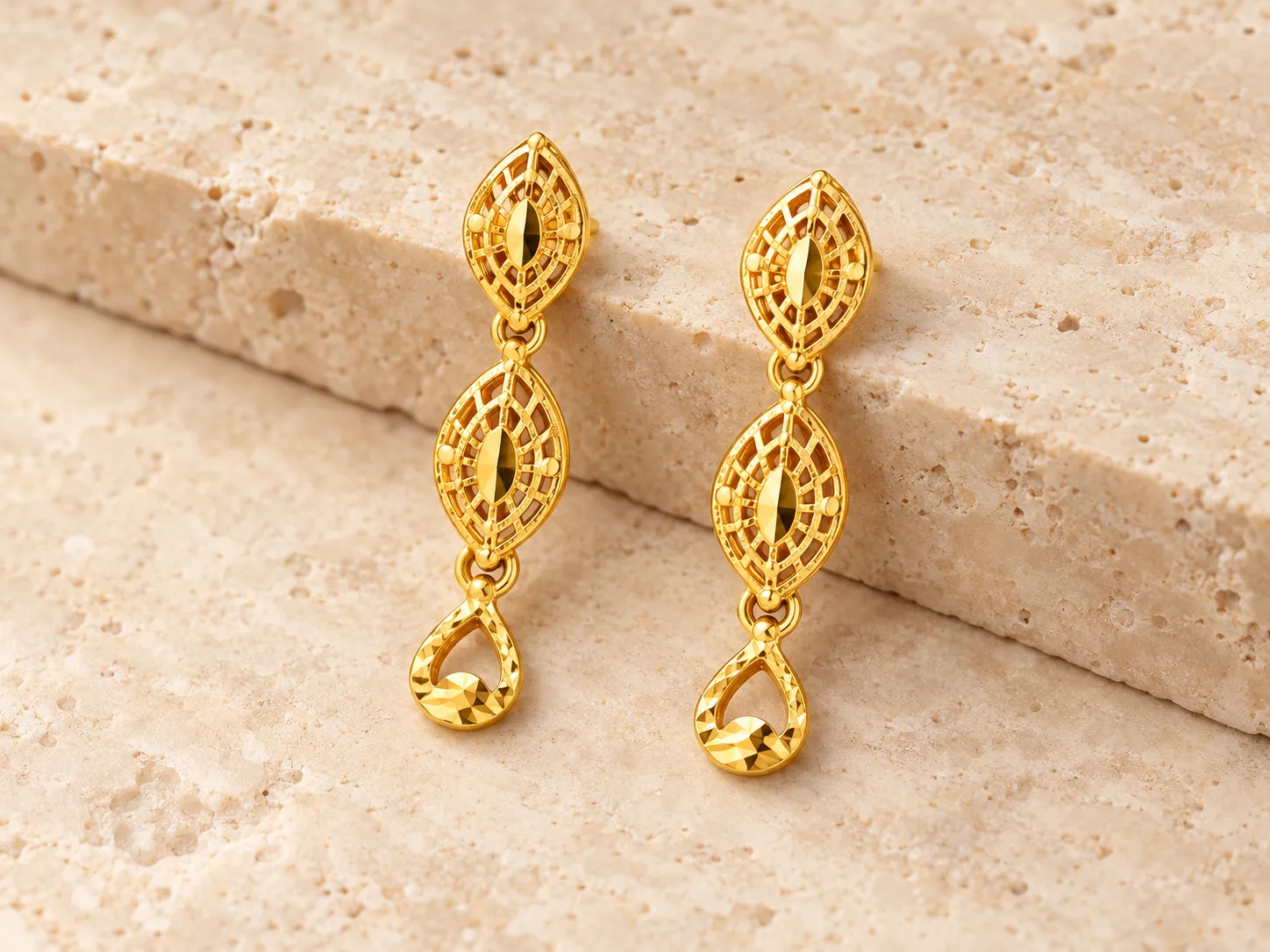 Pair of gold drop earrings with leaf-shaped openwork links and a teardrop end