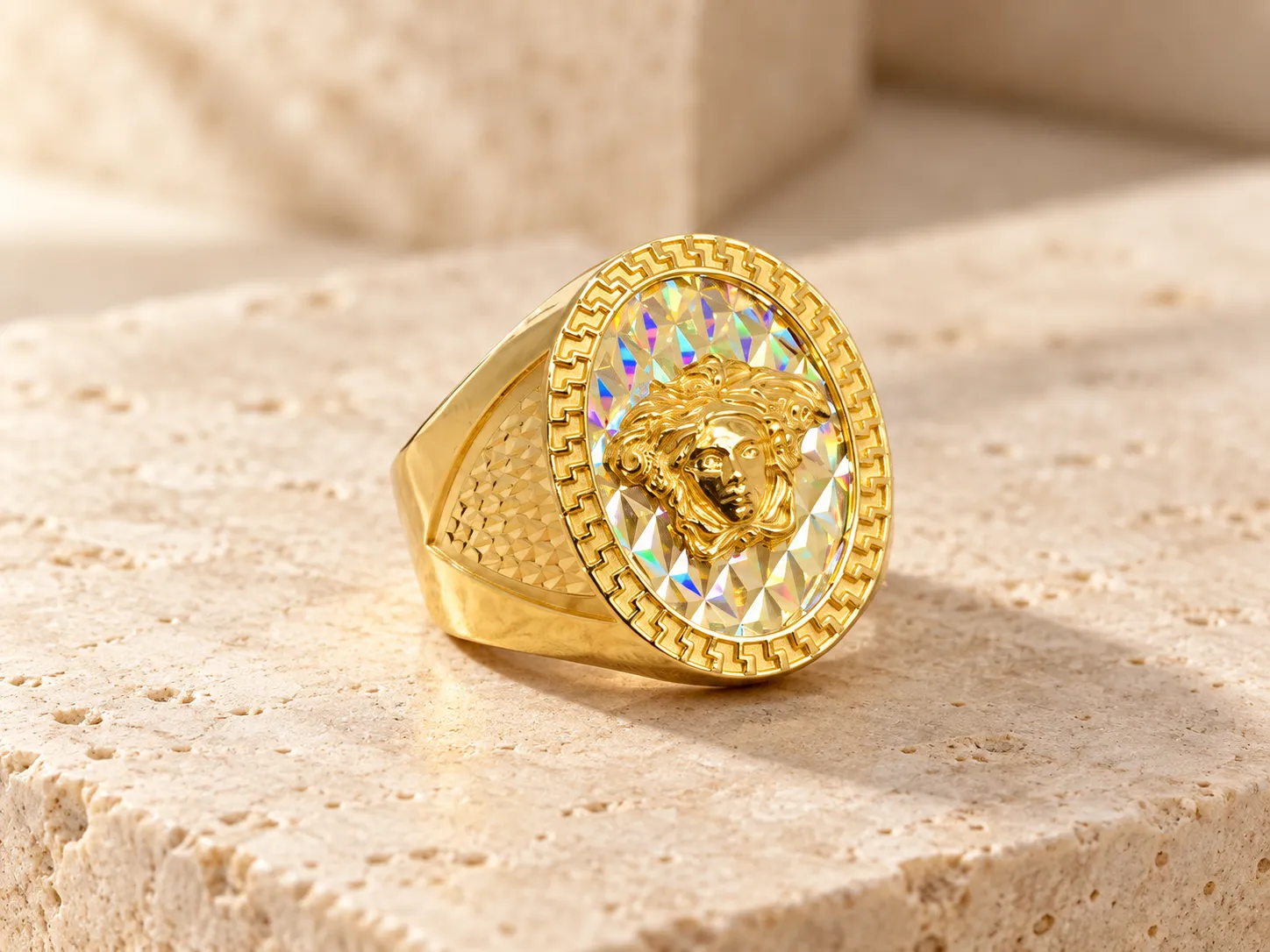 Gold signet ring with a sculpted head on a prismatic oval face with a Greek-key border and textured shoulders, on a stone ledge