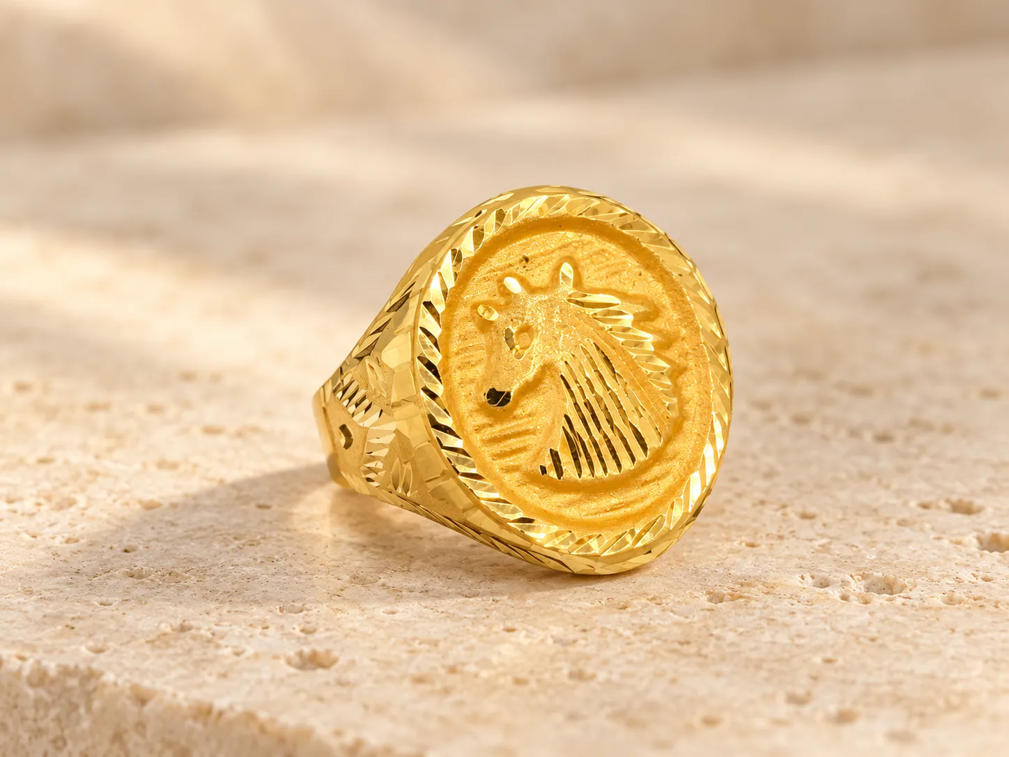 Gold signet ring with a horse head in profile in relief on an oval face with a ridged edge, on a stone ledge
