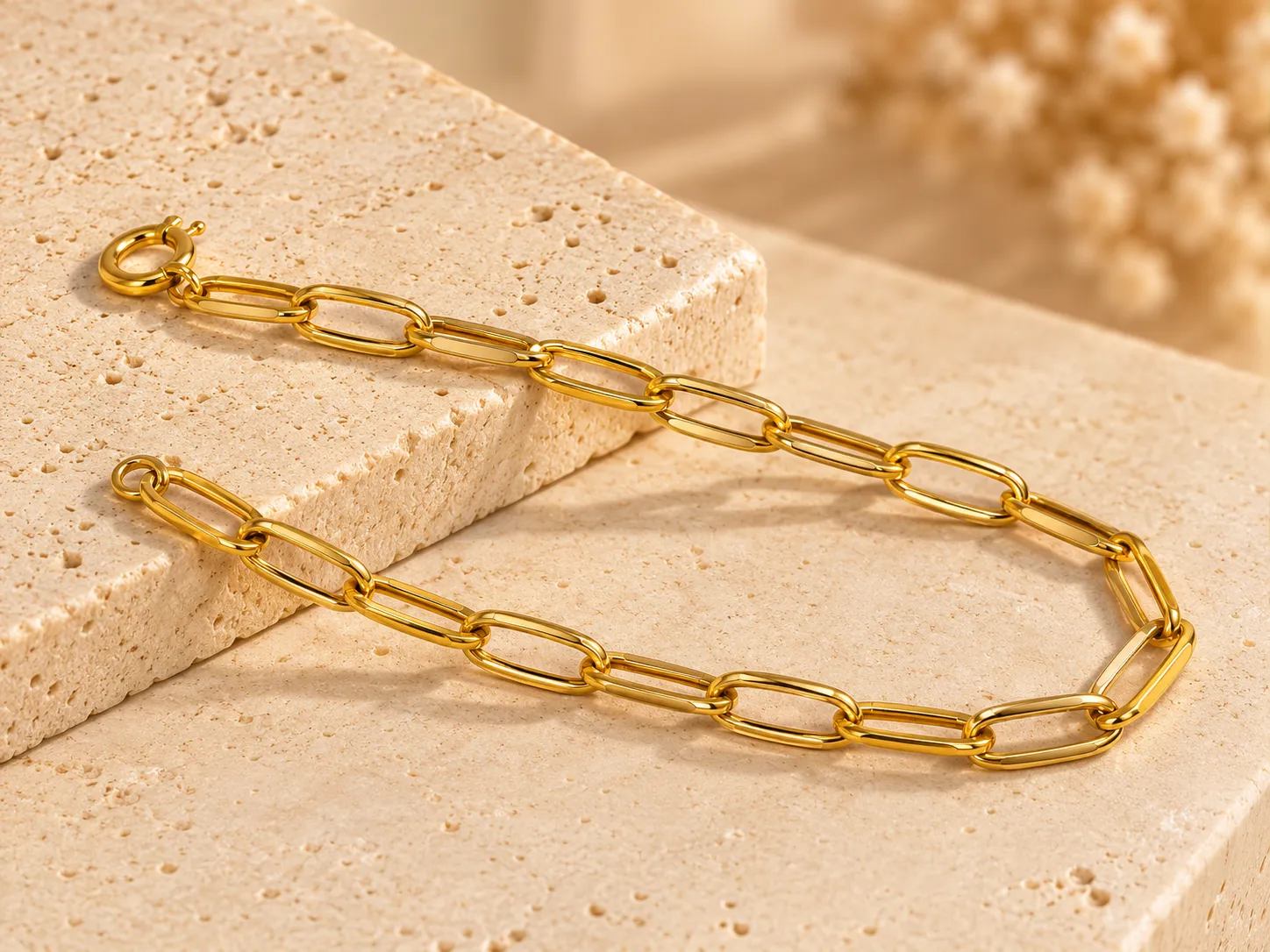 Gold bracelet of elongated paperclip-style links with a ring clasp, on a stone slab