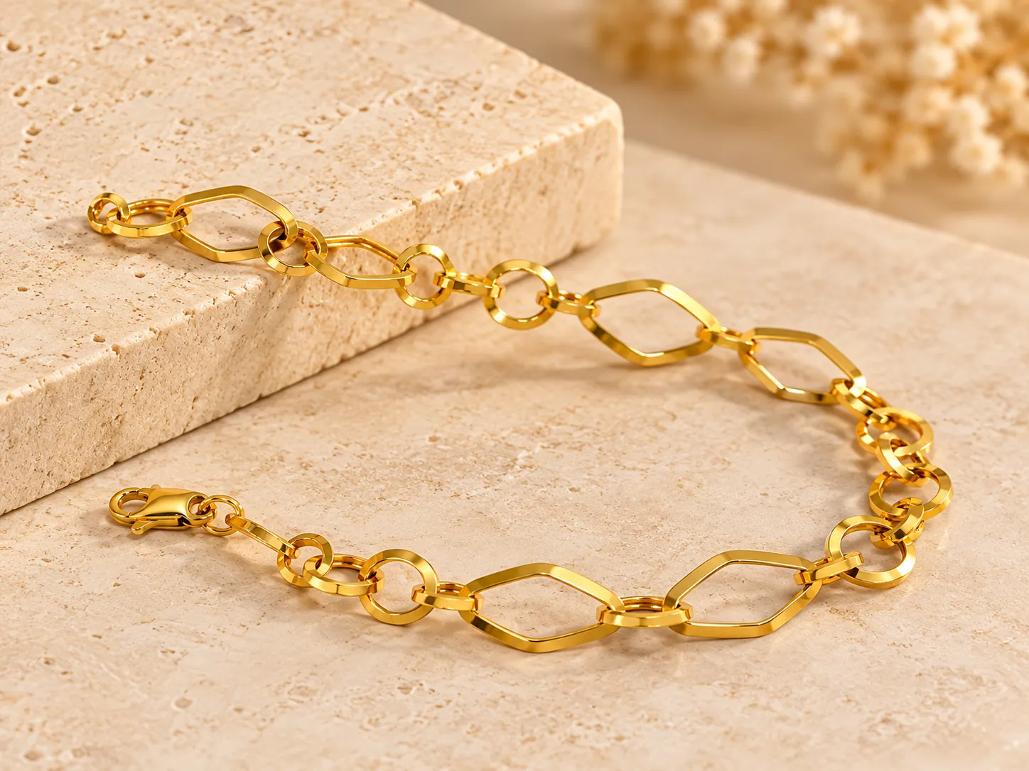 Gold bracelet of open marquise-shaped links with rounded connectors, on a stone slab