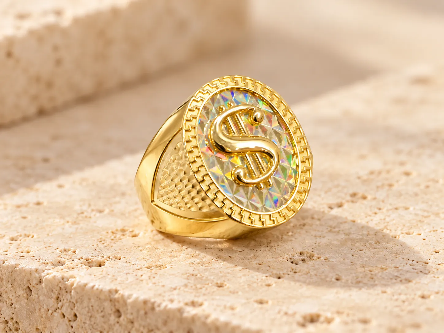 Gold ring with a polished S-shaped emblem on a prismatic oval face with a Greek-key border, on a stone ledge
