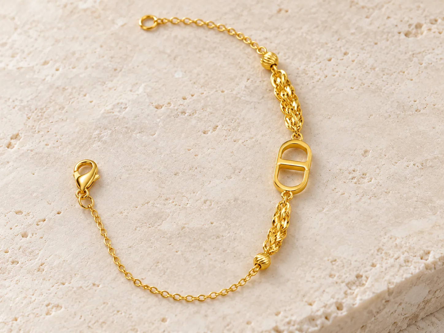 Gold bracelet with a fine chain and a central link, photographed on a warm stone surface