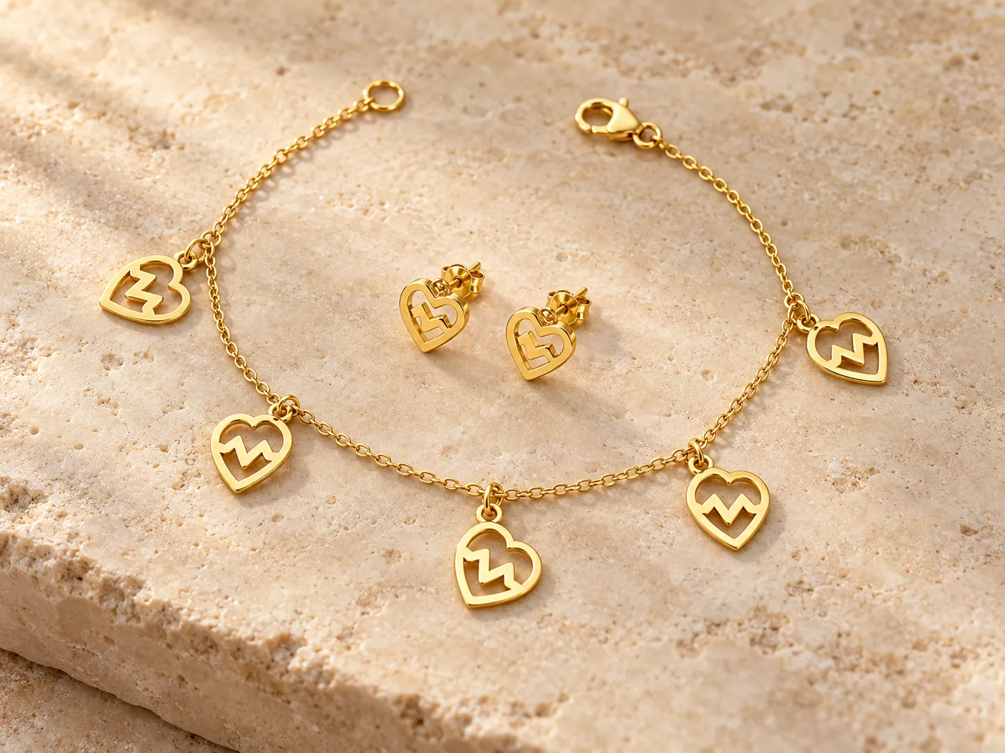 Gold charm bracelet with heart-shaped cut-out charms beside a pair of heart-shaped earrings