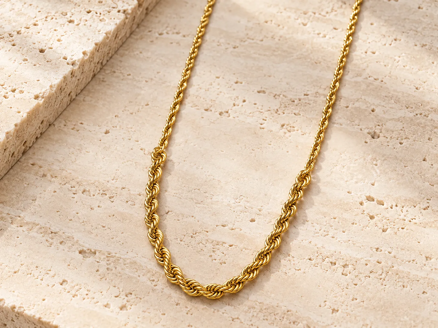 Thick gold twisted rope-style chain necklace hanging over a stone ledge