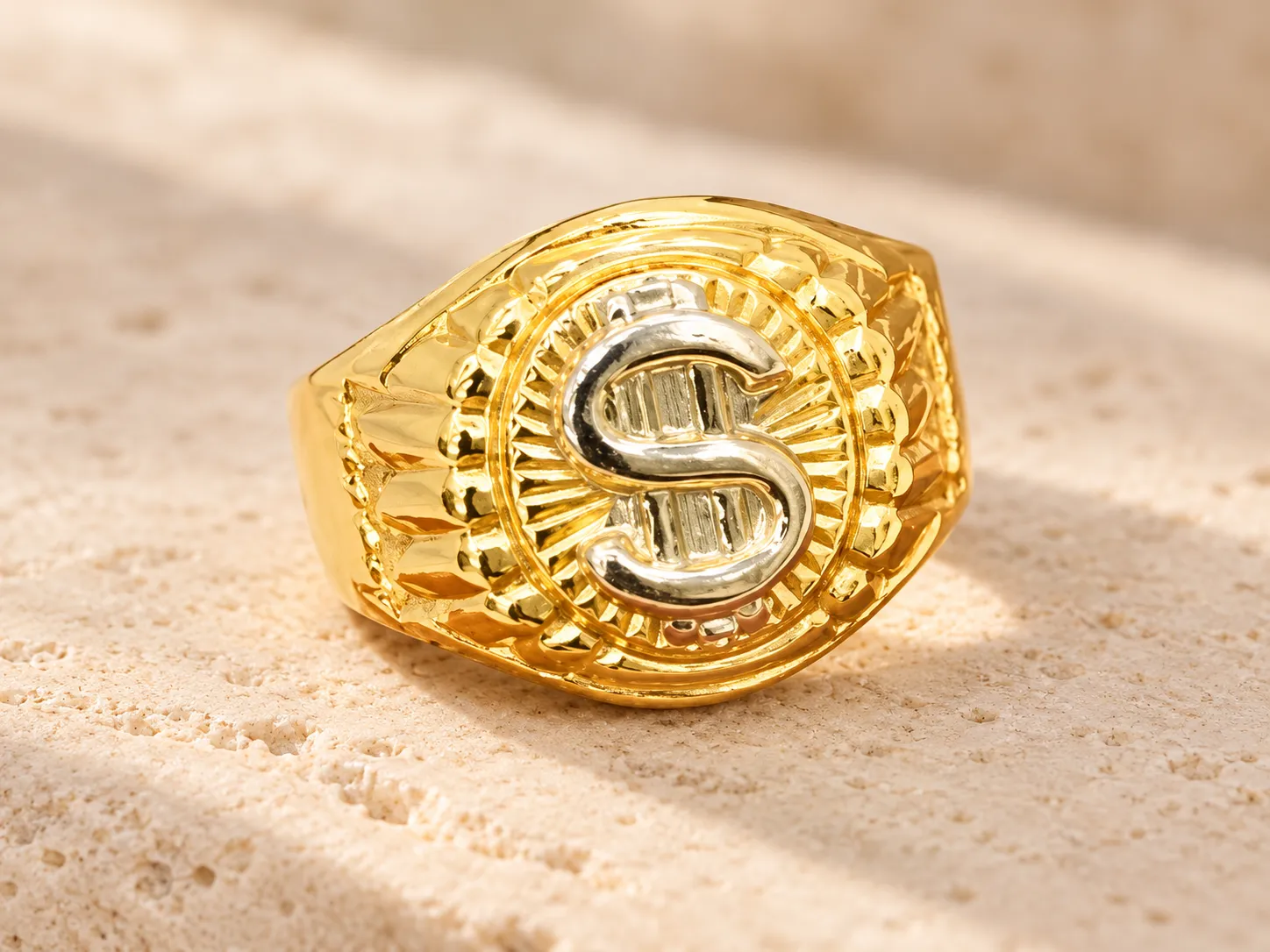 Gold ring with a silver-toned dollar sign inside a ridged oval