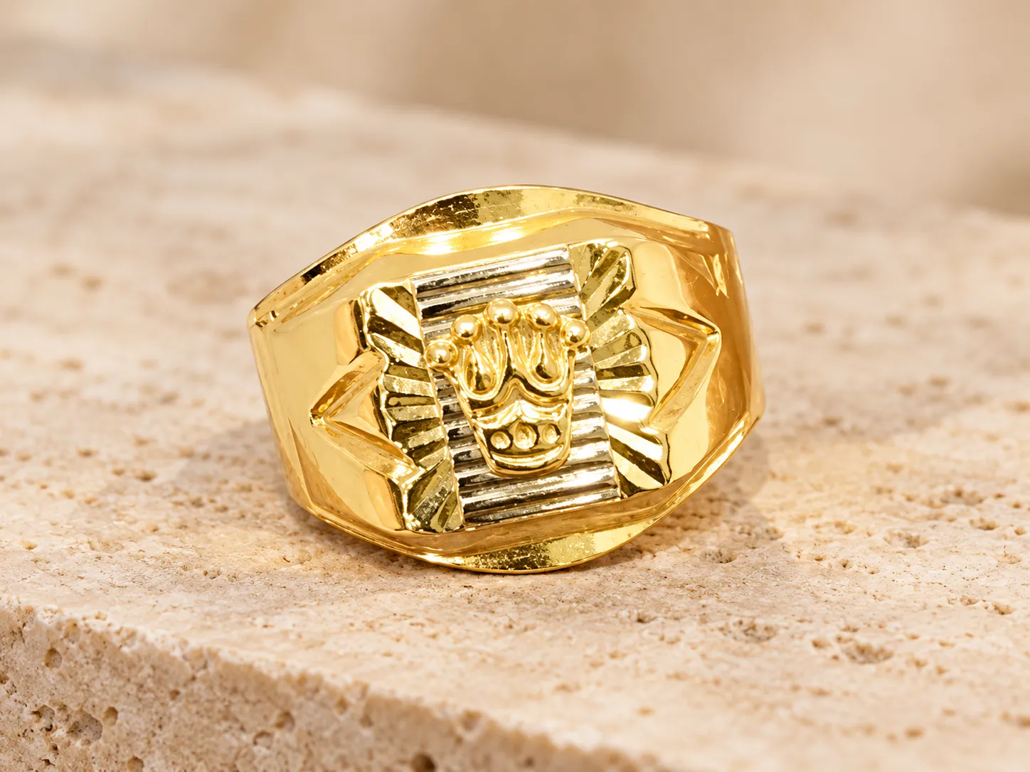 Gold signet ring with a raised silver-toned emblem on a rectangular face